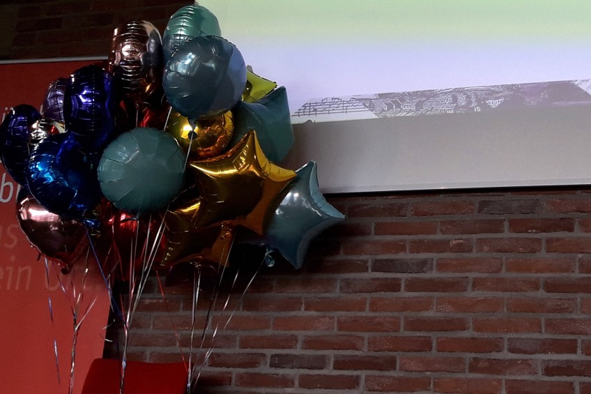 Ein Bündel mit Gas gefüllter Ballons vor einer Klinkermauer.