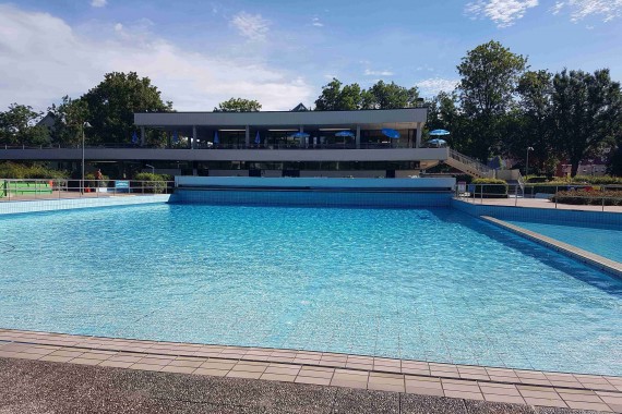 Ruhiges Wellenbecken im Inselbad mit Gebäude im Hintergrund
