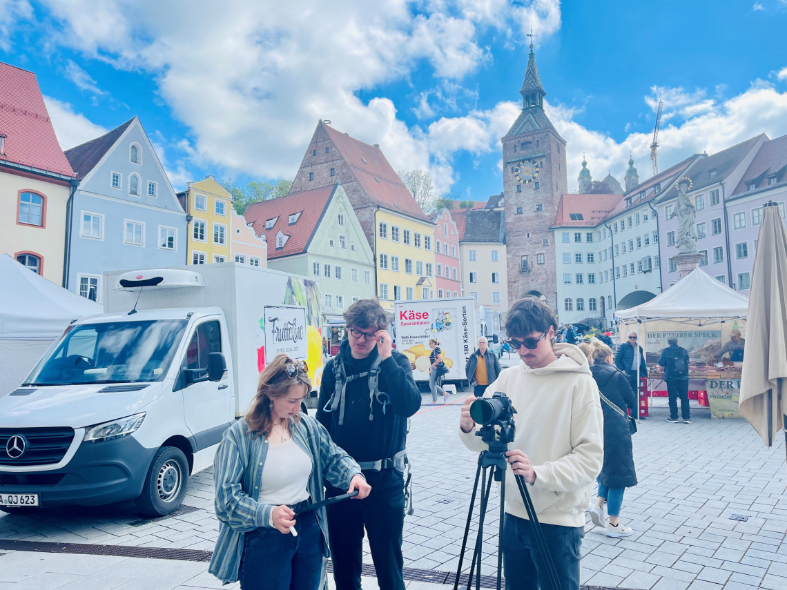 Dreierteam beim Filmen inmitten des Wochenmarkts am Hauptplatz.