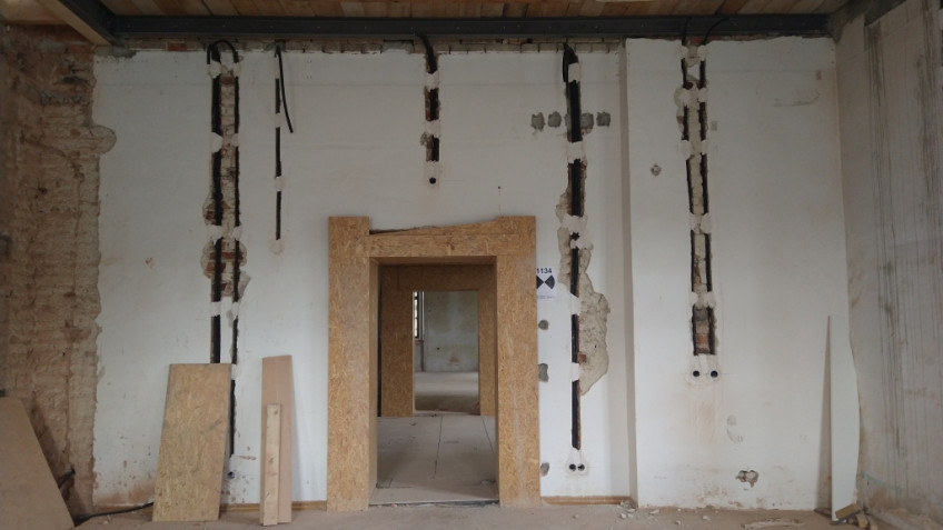 Senkrecht in einer weißen Wand verlaufen fünf offene Kabelschächte.