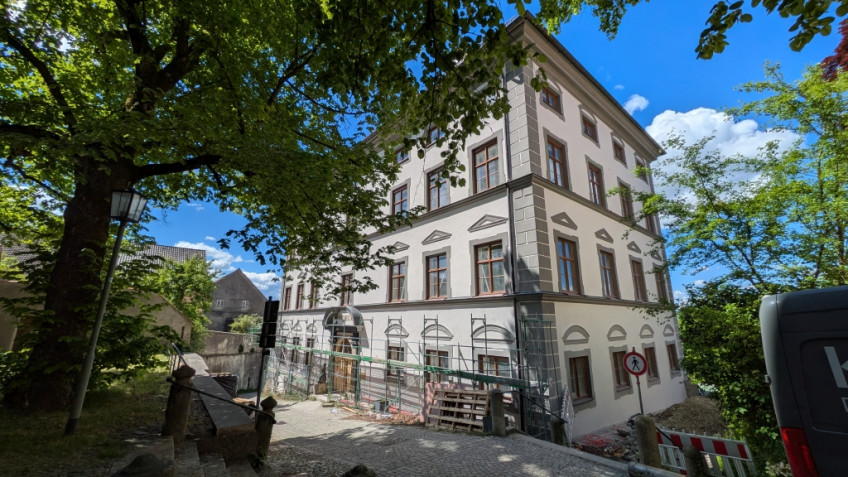 Nordostseite des frisch gestrichenen Museumsgebäudes, gerahmt von Bäumen. Das Baugerüst deckt nur noch das Erdgeschoss ab.