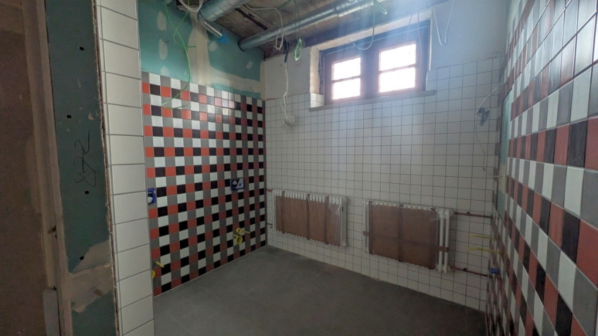 Ein kleiner Raum ist an zwei Seiten mit kleinen roten, weißen, grauen und schwarzen Fliesen versehen.