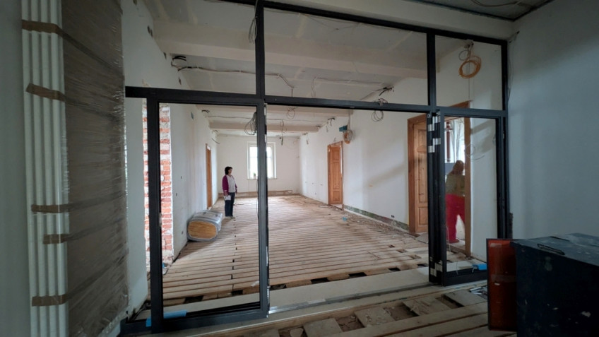 Flur mit offenliegendem Bretterboden und Dämmmaterial auf Rollen.