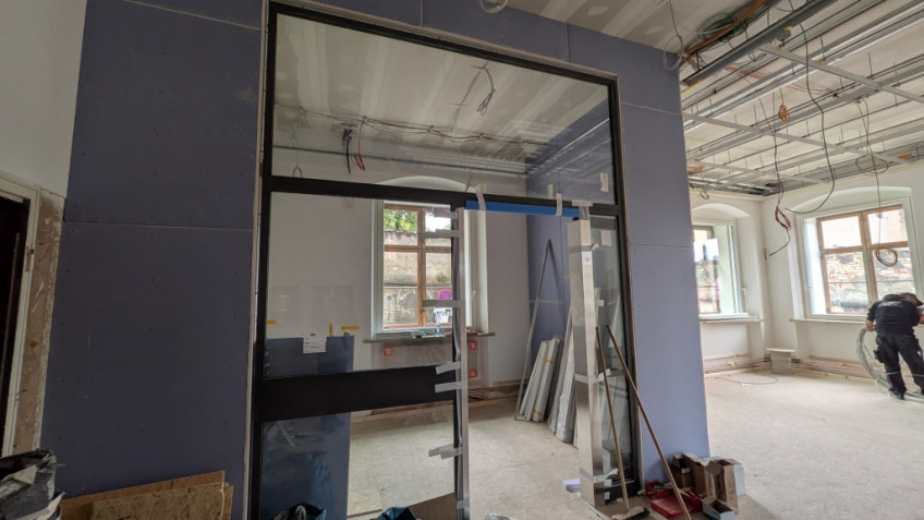 Im Raum bilden blaue Trockenwände und eine Glaswand einen Büroraum.