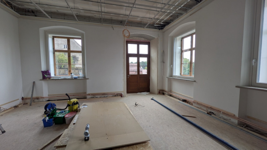 Raum mit großen Fenstern und dunkler Holztür