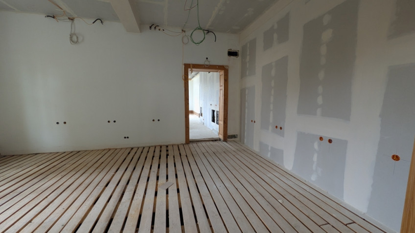 Raum mit neuer Trockenwand rechts und freiliegenden Bodenbrettern
