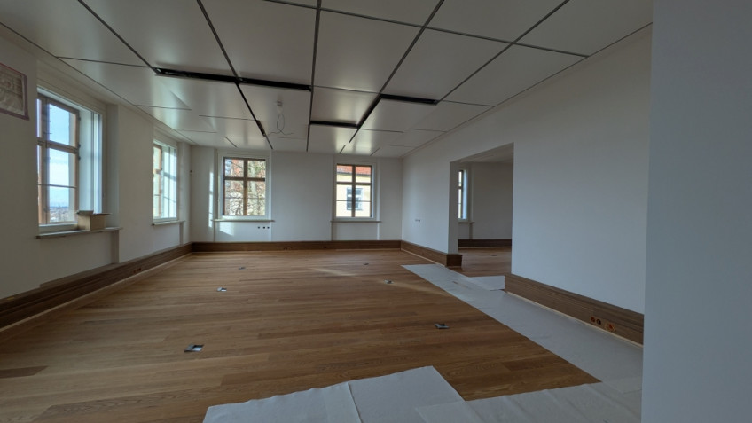 Raum mit wei&szlig;en W&auml;nden, wei&szlig;en Decken und frisch verlegtem Parkettboden.