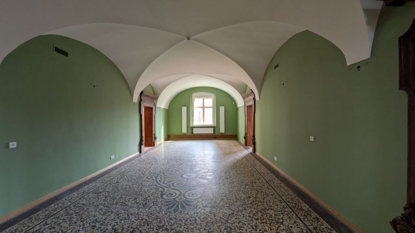 Flur mit wei&szlig;er Gew&ouml;lbedecke und gr&uuml;nen W&auml;nden auf ein Fenster zuf&uuml;hrend